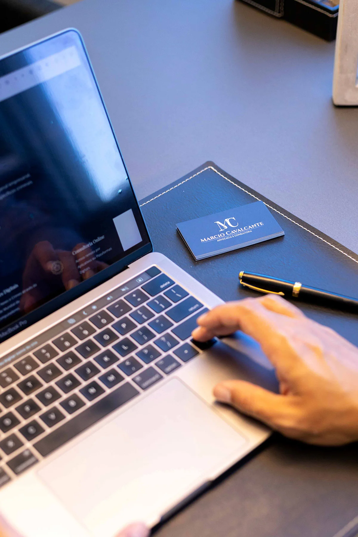 Mesa de trabalho do escritório com notebook e cartão de visita Marcio Cavalcante